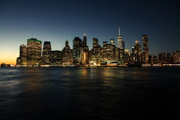 Fototapeta na wymiar New York Manhatten Skyline aus Brooklyn, Sonnenuntergang mit Lichtern