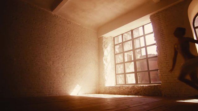 Female ballet dancer trains in room with large window