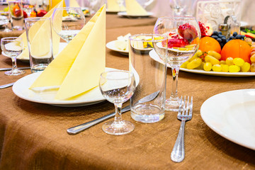 The table in the restaurant. On the table there are empty wine glasses, napkins and plates. Also in the picture you can see fruit plate