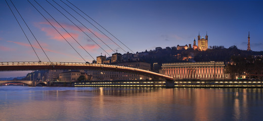 Panorama of a footbridge over the Saone river in Lyon, France, during twilight.