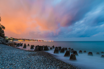 Obraz premium Long exposure photo of the concrete conical boulders lying in the sea on the background of coastline of Sochi at dawn, Russia 