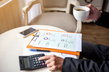 Fototapeta premium Man using calculator and writing make note with calculate and drink coffee at work