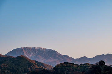 大山の山肌を朝日が照らす秋の終わり