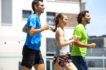 Two young men and woman running in urban enviroment