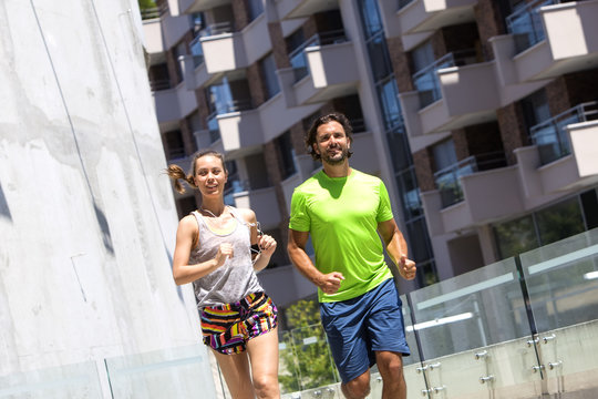 Young couple jogging for fitness in urban environment on summer day
