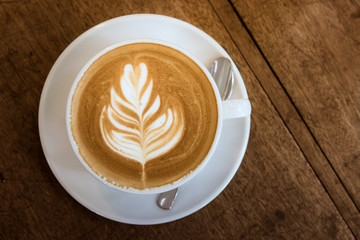 Cup of hot latte art coffee on wooden board