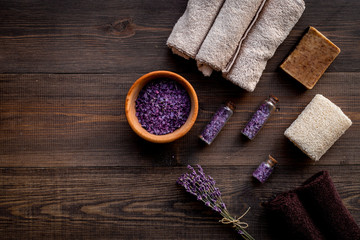 Floral foot spa with lavender. Spa salt, sponge, soap, towel on dark wooden background top view copyspace