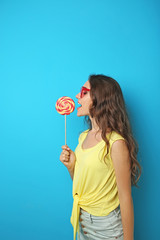 Portrait of young woman with lollipop on blue background