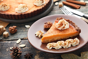 Sweet piece of pumpkin tart in plate on wooden table