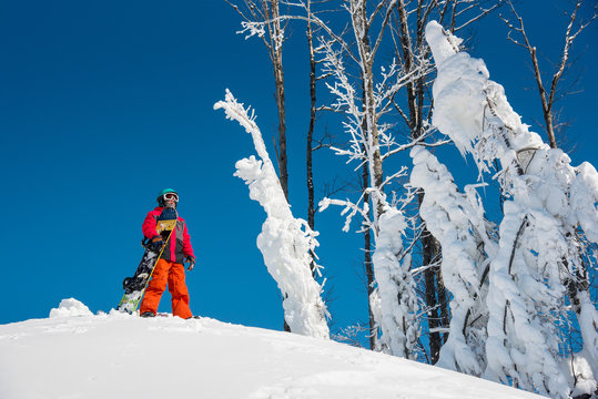 Shot of a snowboarder standing on top of the mountain with his snowboard on a sunny winter day copyspace lifestyle enjoyment recreation sportsman activity people seasonal concept