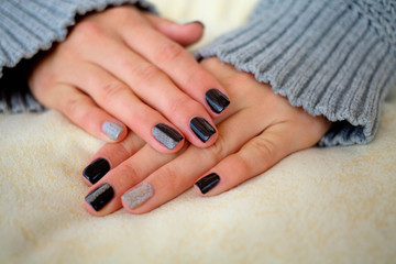 Beautiful hands with manicure in a knitted warm sweater.Manicure - Beauty treatment photo of nice manicured woman fingernails.