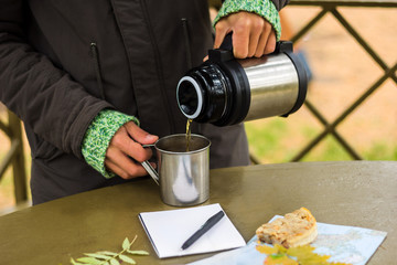 Fototapeta na wymiar man pours tea from a thermos on a picnic in autumn park
