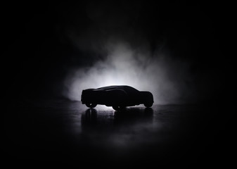 The car in the shadows with glowing lights in low light, or silhouette of sport car dark background