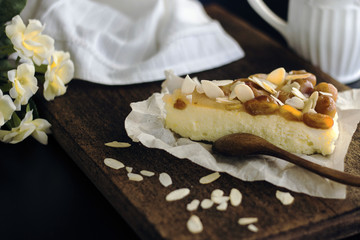 slice of cheese cake with cherry topping and almond flakes on a wooden old surface