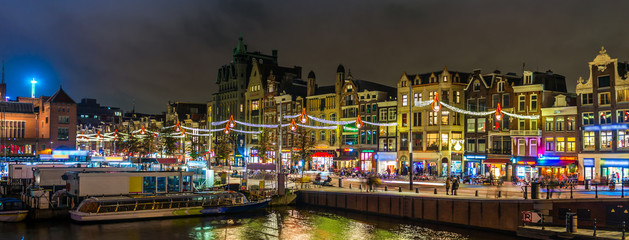 Fototapeta premium La Damrak de nuit à Amsterdam en Hollande aux Pays-Bas