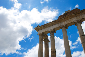 Naklejka premium Rome. The Temple of Saturn in the Roman Forum. In the background blue sky and clouds.