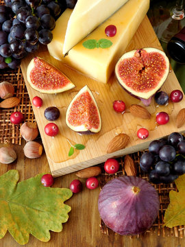 Parmesan on a board surrounded by figs, grapes and honey. Ingredients for a cheese plate