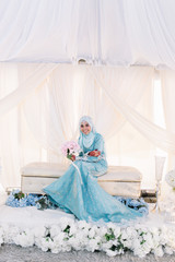 Fototapeta na wymiar Portrait of attractive young woman in Malay or Asian traditional wedding dress sitting on bridal dais. Love and marriage concept.