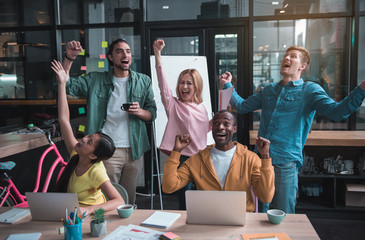 Our success. Cheerful international qualified young team members are screaming and expressing their positive emotions while finishing important business project