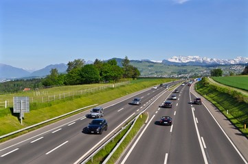  A3 - Autobahn mehrspurig zwischen Zürich und Chur. Autos beim fahren, Im Hintergrund Schweizer Schneeberge,   - obrazy, fototapety, plakaty
