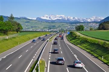 Autobahn A3 von Zürich nach Chur - mit fahrenden Autos - im Hintergrund Schweizer Berge im Schnee, Schweiz - obrazy, fototapety, plakaty