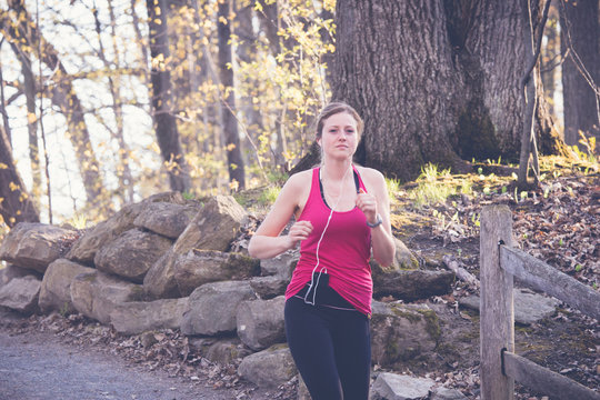 Beautiful young woman runner in a forest trail