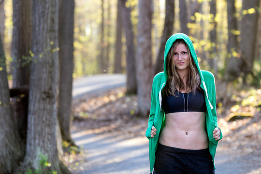 Happy fit woman outside in nature wearing sport bra and sweatshirt