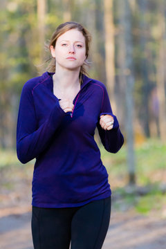 Female runner athlete running on forest trail.