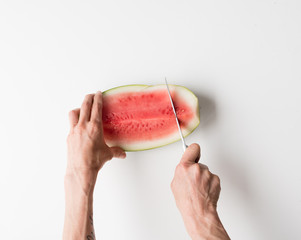 HIgh angle cropped view of woman's hand cutting watermelon slices