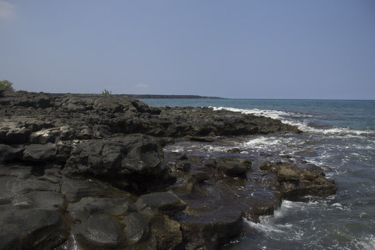 Black lava rock beach with crashing ocean waves