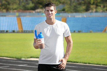 Man holding bottle with protein shake at sport stadium