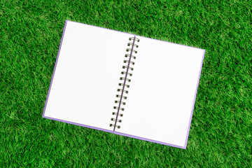 Blank spiral notebook with line paper on green grass