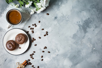 Chocolate cupcakes with a cup of hot black coffee on cocrete background. Top view