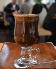 Black coffee on a glass cup on a wooden table.