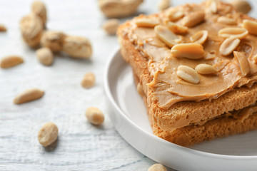 Plate of tasty toasts with peanut butter on wooden table, closeup