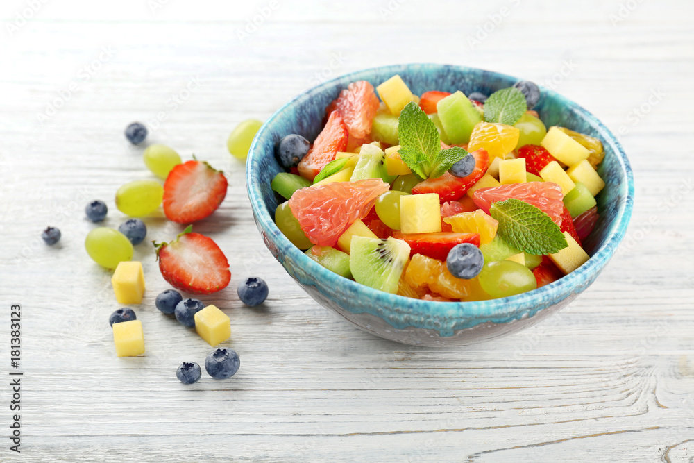 Sticker bowl of fresh fruit salad on wooden table