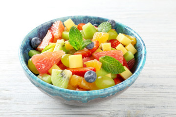 Bowl of fresh fruit salad on wooden table