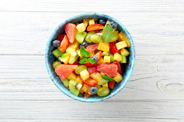 Bowl of fresh fruit salad on wooden table