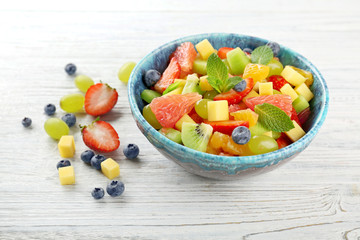 Bowl of fresh fruit salad on wooden table
