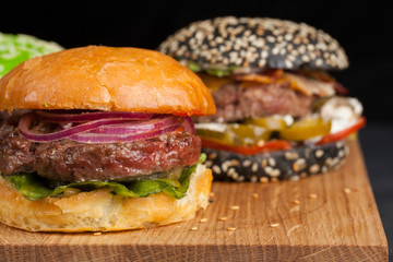 Closeup of set of three mini homemade Burger with marble beef and vegetables on a wooden Board