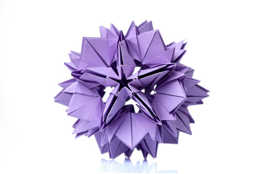 Violet flower origami on white. Wonderful figurine made of folded colorful paper. Piece of craftsmanship.