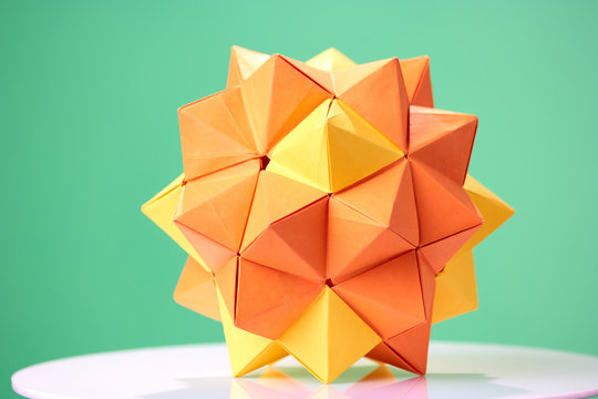Dodecahedron origami on green background. Beautiful 3D paper model as item of exposition. Child's talent and creativity.