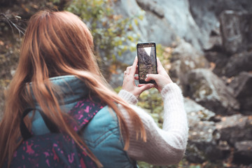 Рыжеволосая девушка фотографирует природу на смартфон