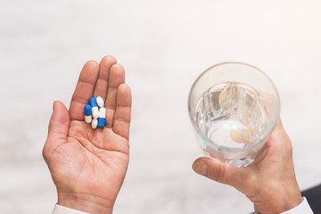 Adult woman holding pills and glass of water. Top view. Health care concept.