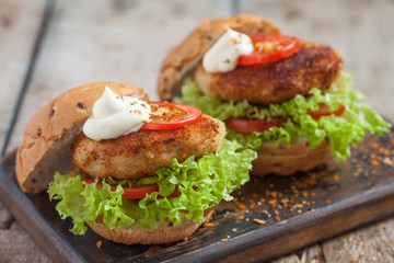 chicken burgers with vegetables on a wooden table