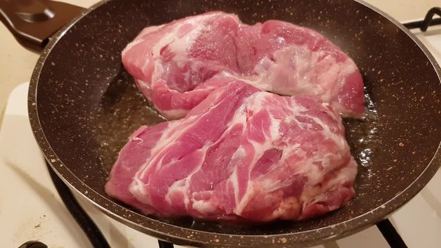 Juicy appetizing steaks from fat pork fried in a pan with olive oil
