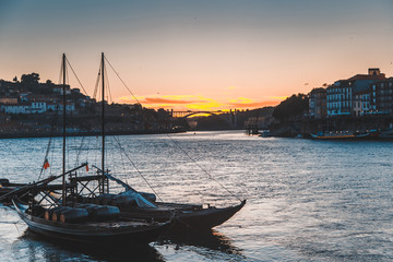 Boats carrying barrels of porto wine seen docking at river bank at sunset time at Porto, Portugal....