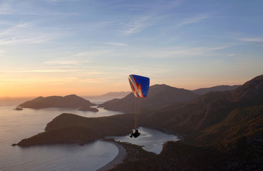An unidentified paraglider flying at sunset over Blue lagoon in Oludeniz, Turkey
