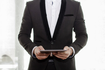 Businessman in black suit hand holding tablet on coffee shop.Copy space fore your text