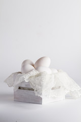 eggs in a white wooden box and lace on a white background